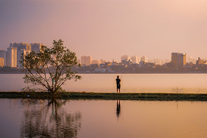 Fishing at sunset with magnificient view of Hanoi from West lake 